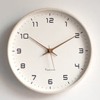 White wood wall clock with white face on a plain wall