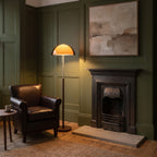 Aalen amber floor lamp lit beside a leather club chair in an olive green Victorian sitting room