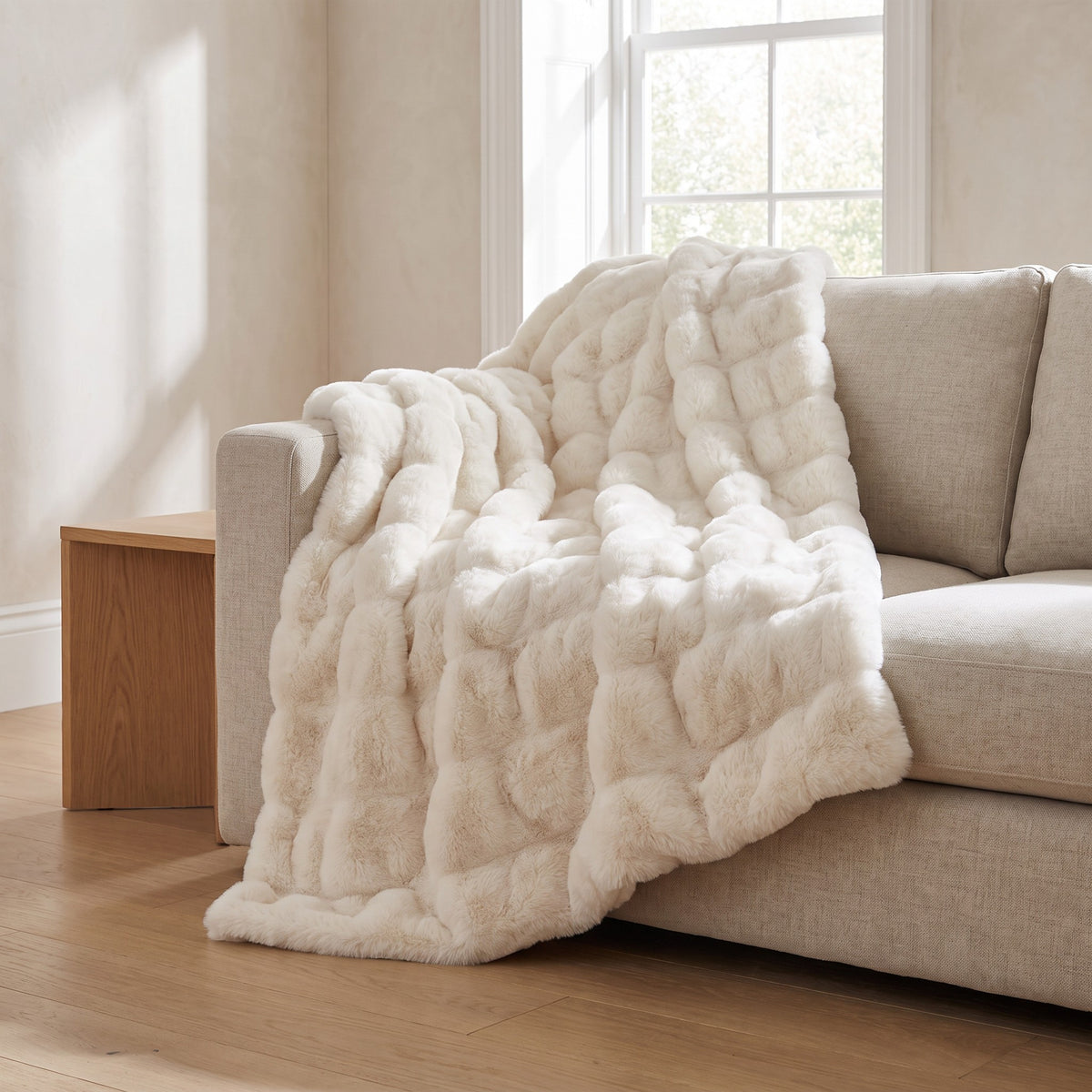 Gent cream faux fur throw draped over a linen sofa