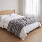 Gent grey faux fur throw across the foot of a made bed