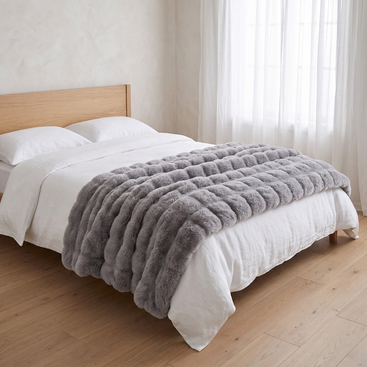 Gent grey faux fur throw across the foot of a made bed