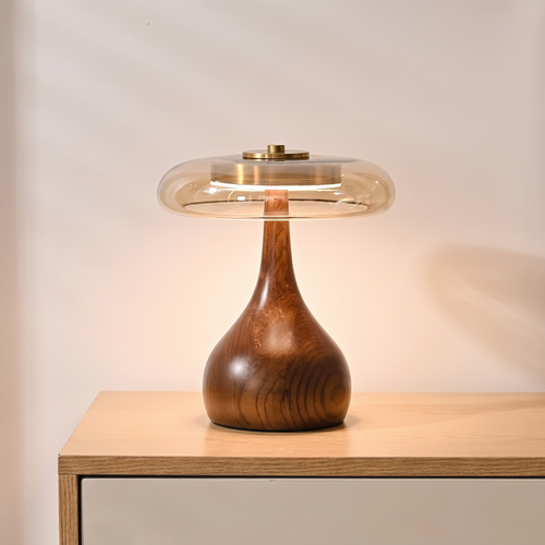 Amber glass table lamp glowing on a walnut console