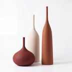 Trio of brushed ceramic vases in cream, rust and oxblood on a white background