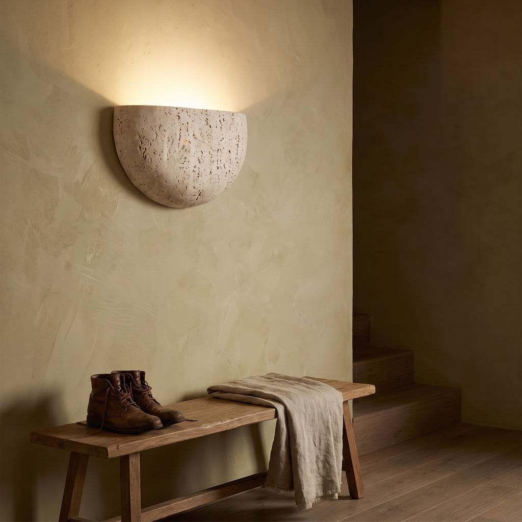 Inglecote travertine wall light above an oak bench in a plastered hallway