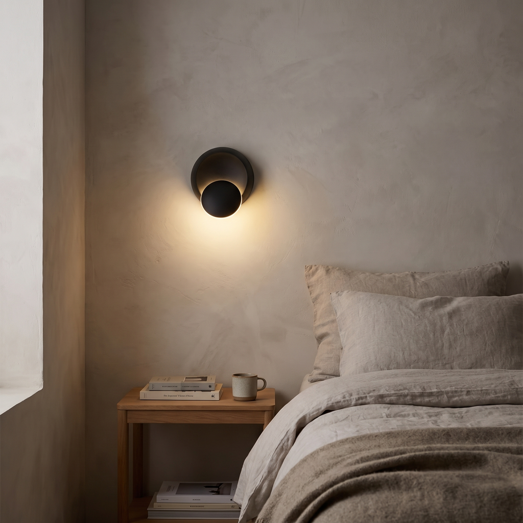 Ilmenau black wall light glowing beside a bed