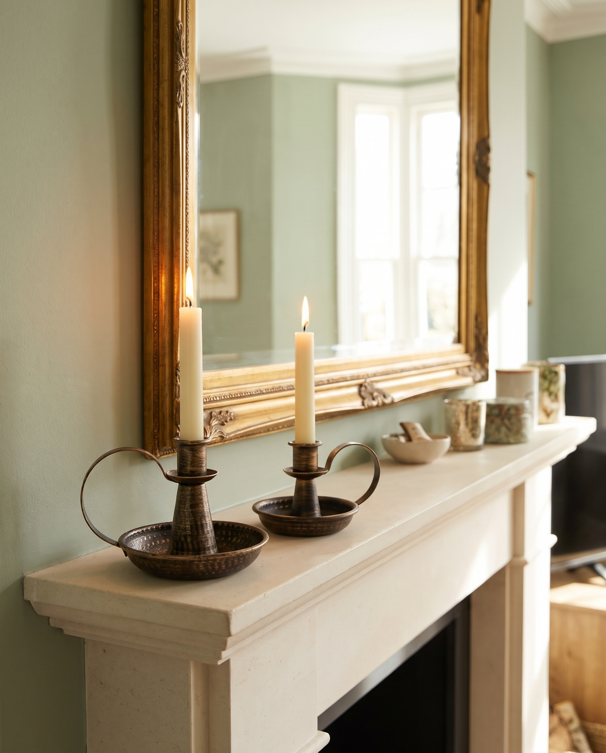 Hoganas chamberstick candle holders with lit tapers on a stone mantelpiece