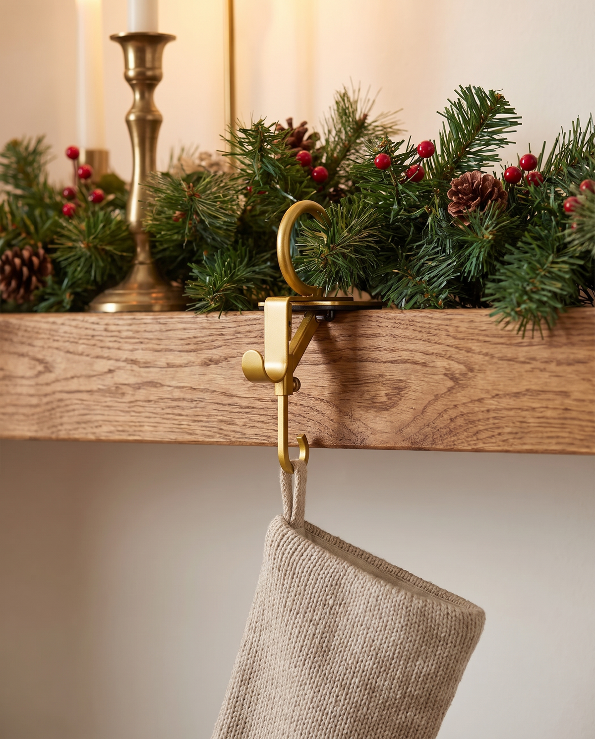 Gold Esens hanger holding a garland and an oatmeal stocking on an oak mantel