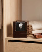 Lahr watch winder on a wardrobe shelf beside folded knitwear