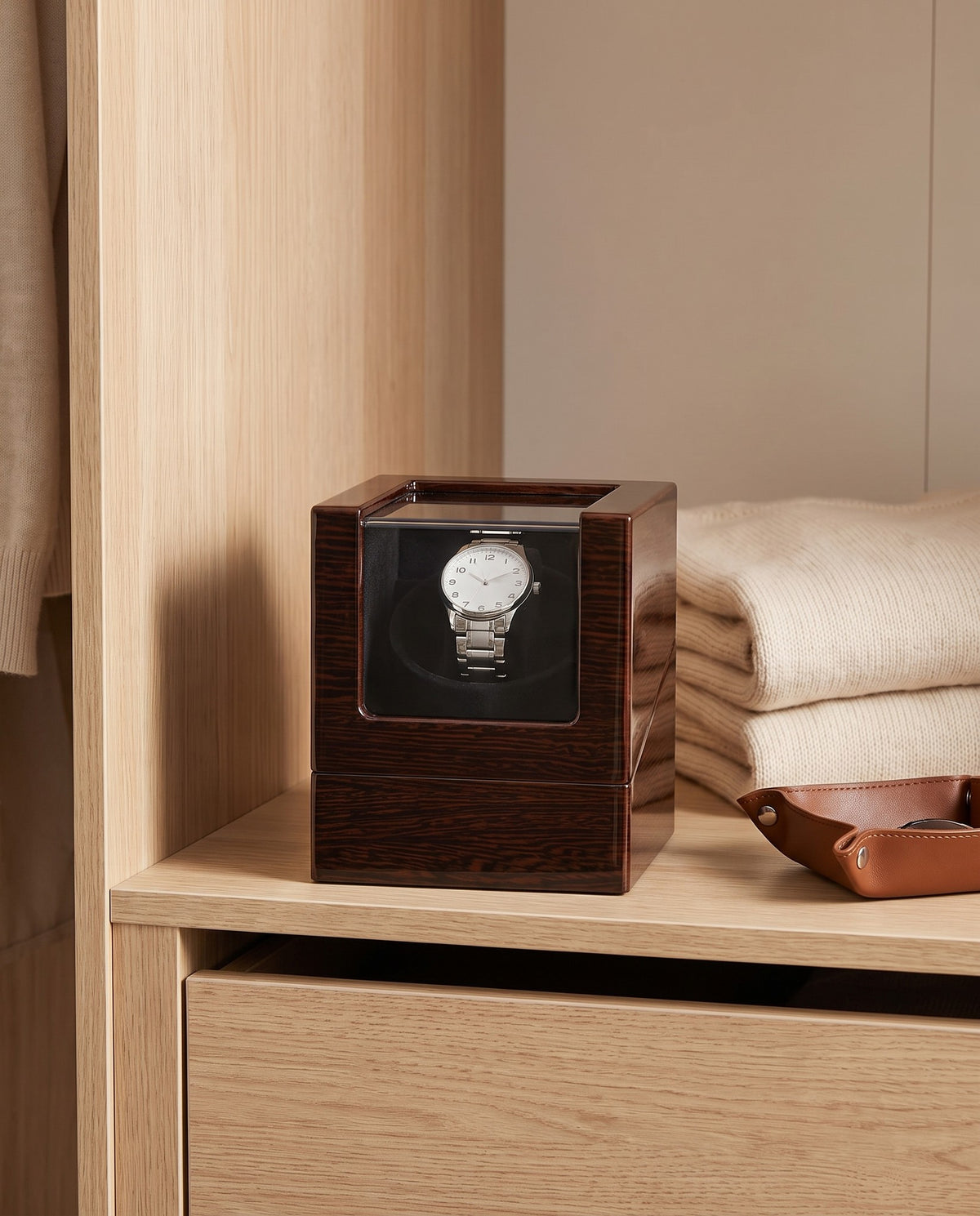 Lahr watch winder on a wardrobe shelf beside folded knitwear