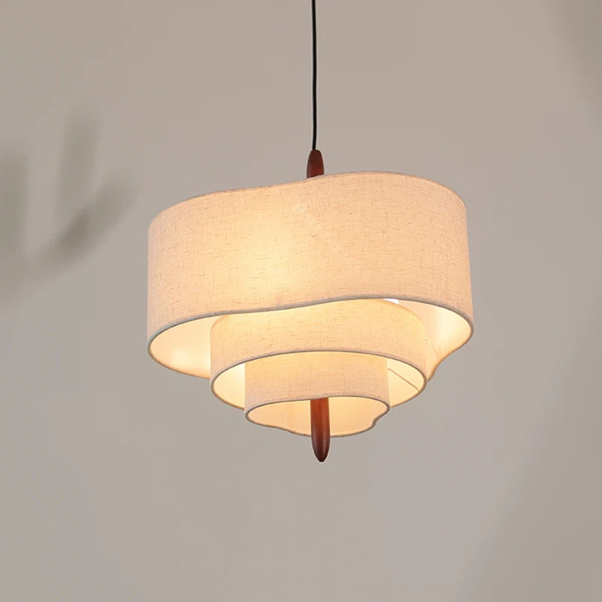 Lauenburg tiered fabric chandelier lit, product photo showing the waved tiers and wood finial