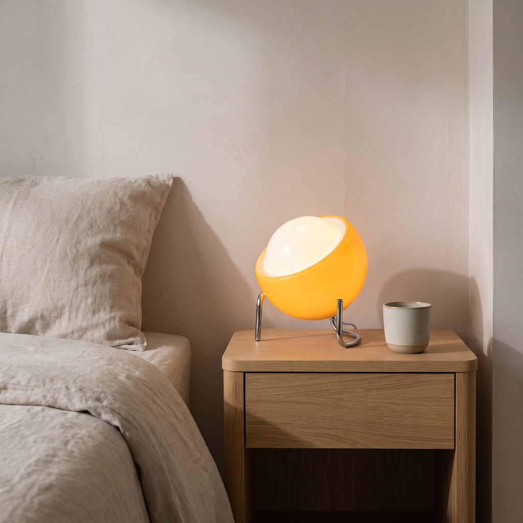 Lugano orange glass globe lamp glowing on an oak bedside table