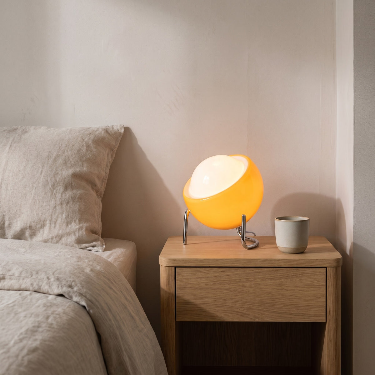 Lugano orange glass globe lamp glowing on an oak bedside table