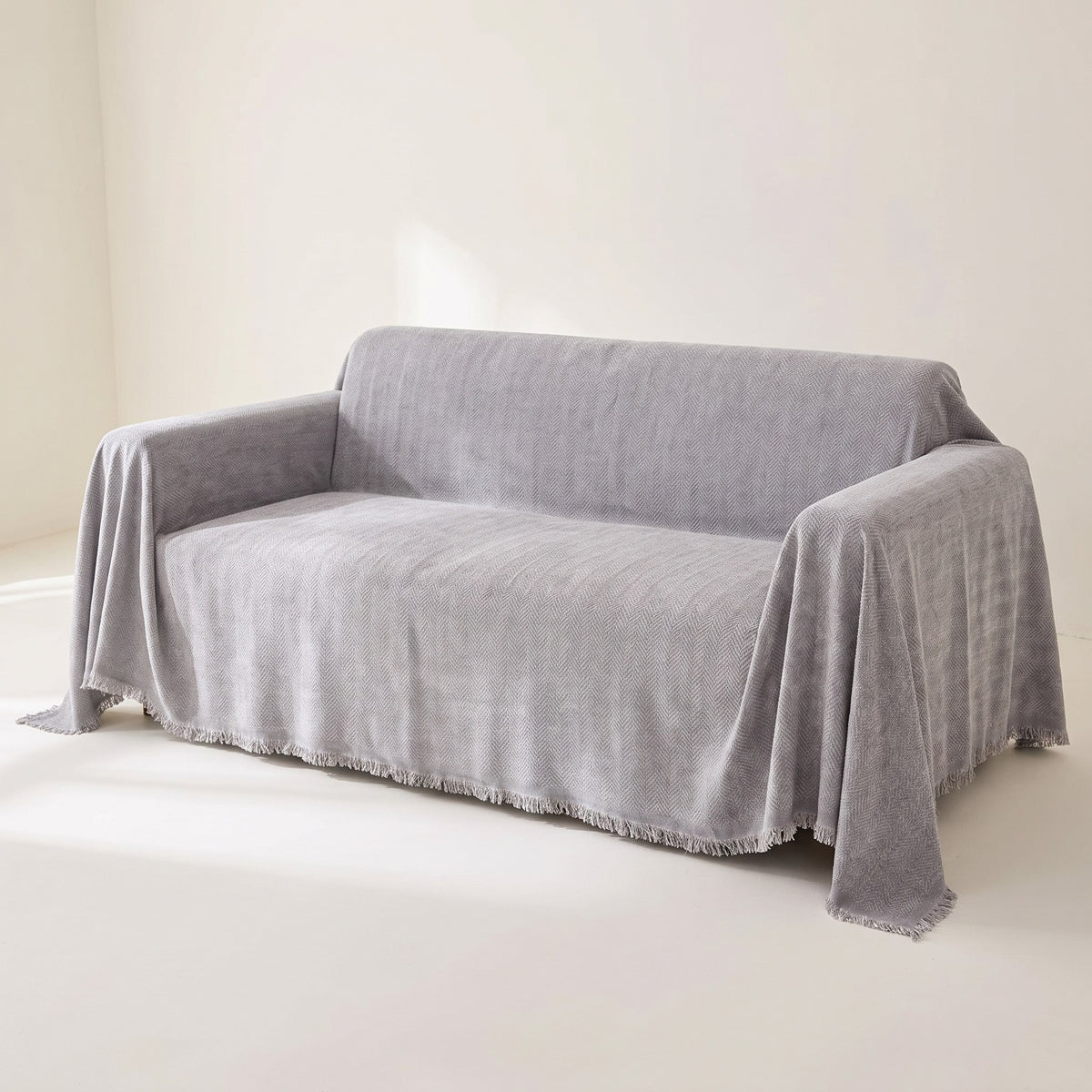 Mariefred herringbone chenille sofa throw in Stone Grey draped over a sofa