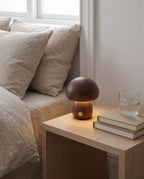 Walnut Molln mushroom lamp glowing on a bedside table