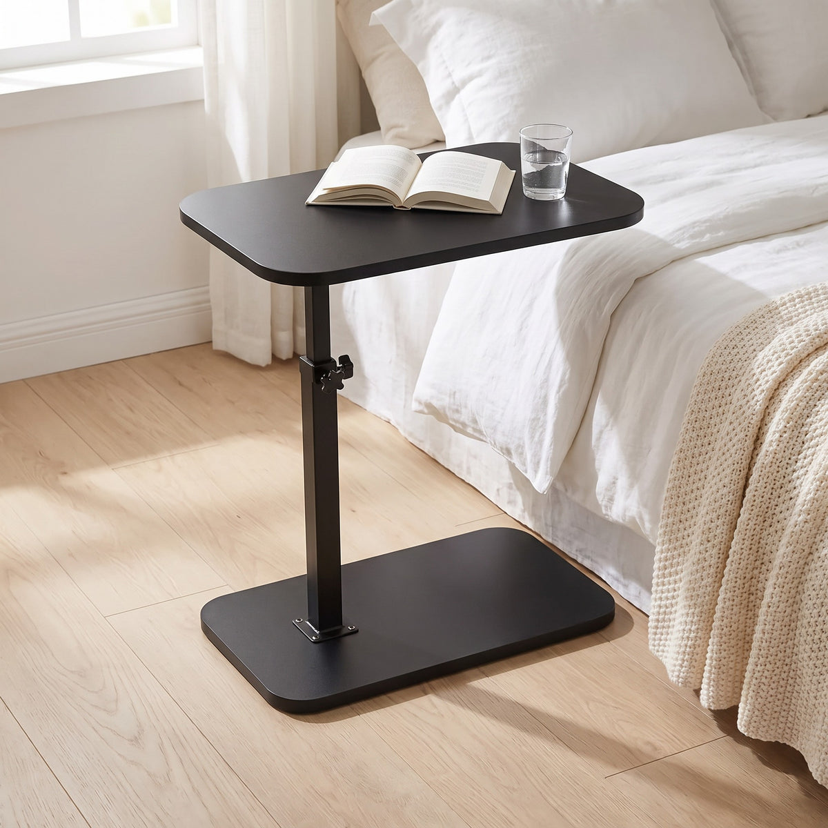 Nordlingen black side table beside a bed with a book and a glass of water