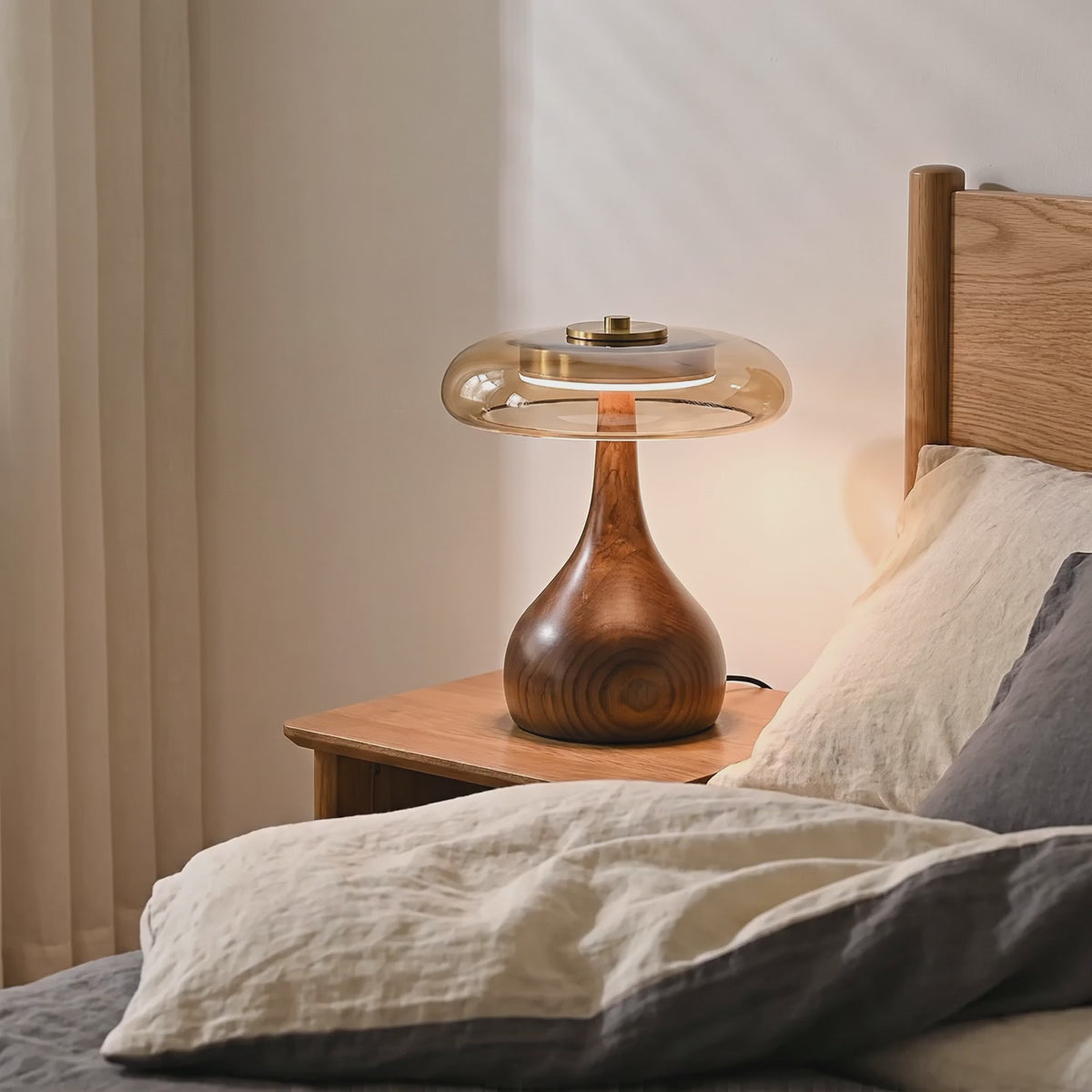 Amber glass table lamp glowing on a bedside table