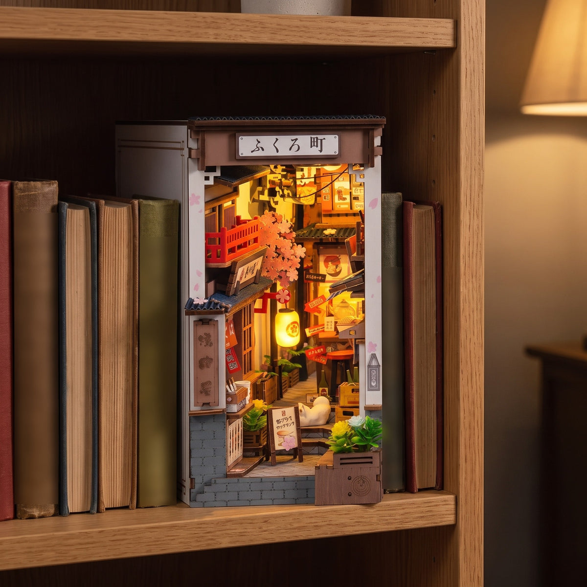 Quedlinburg book nook glowing between hardback books on an oak bookshelf