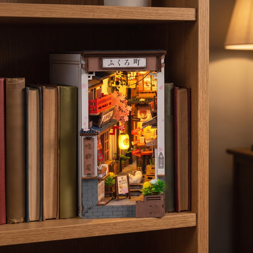 Quedlinburg book nook glowing between hardback books on an oak bookshelf