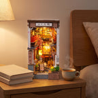 Quedlinburg book nook lit on a bedside table beside books and a cup of tea