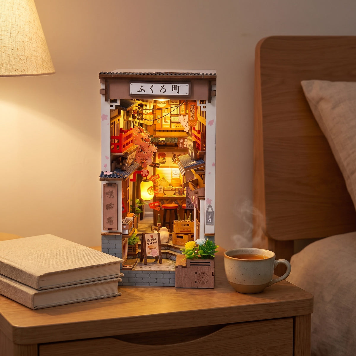 Quedlinburg book nook lit on a bedside table beside books and a cup of tea
