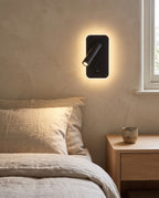 Tonning wall reading light glowing beside a bed with linen bedding