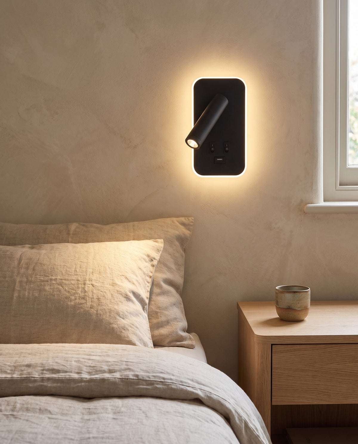 Tonning wall reading light glowing beside a bed with linen bedding